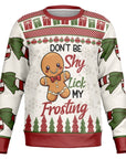 Cream and red Christmas sweater featuring gingerbread man and bold text reading “Don’t Be Shy Lick My Frosting” — playful holiday design from CollegeWares.