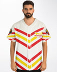 Front view of a man wearing the white baseball jersey with IN-N-OUT-themed red and yellow chevrons and the parody Drum-N-Bass arrow logo printed on the left chest.