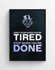 Poster with the full quote “Don’t Stop When You’re Tired. Stop When You’re Done.” in stacked bold text. The words “Tired” and “Done” are highlighted in light purple, emphasizing the visual contrast between when to push and when to rest — a motivational mantra framed by a dark background and the classic top-hat cartoon character above — focused grindset decor from CollegeWares.
