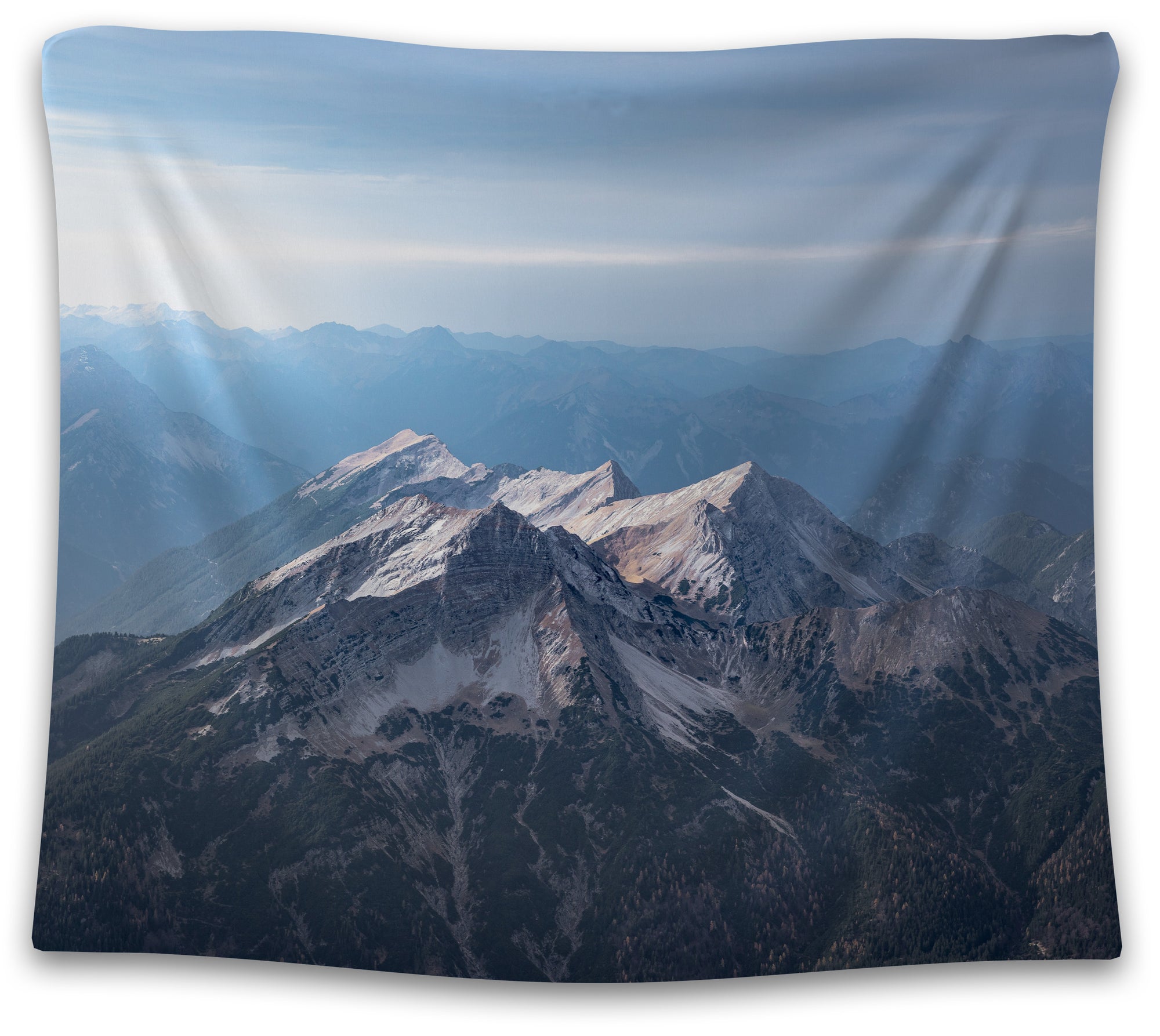 Snow-dusted peaks layered across a distant blue mountain range beneath a hazy sky — scenic high-altitude tapestry from CollegeWares.