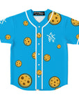 Front of Yookie Crisp EDM baseball jersey on bright blue fabric, covered in floating cartoon chocolate-chip cookies and a small white Yookie logo on the left chest.