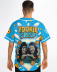 Male model wearing Yookie Crisp baseball jersey back view, showcasing bold logo, cartoon wolf DJs on cookie turntables, and flying cookies over a neon-blue base.